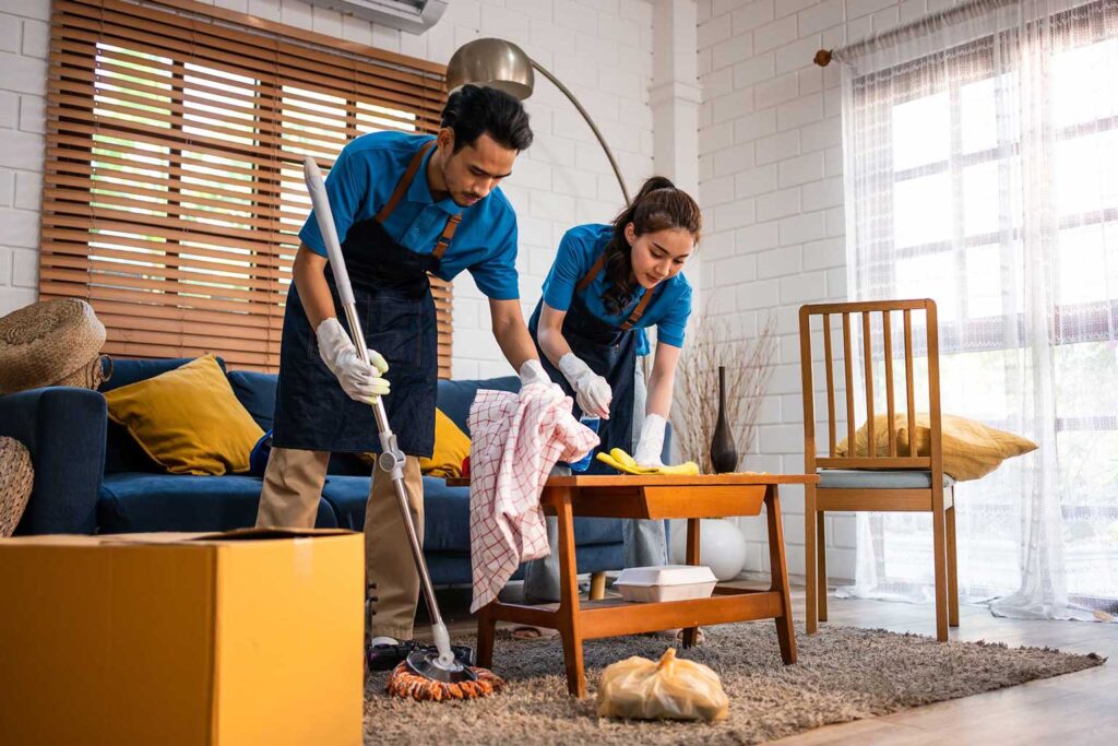A male and woman cleaning service arranging the living and separate the trash.